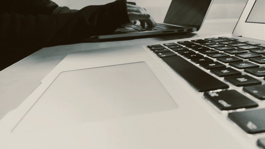 Photo éditoriale : un ordinateur portable ouvert sur un bureau de travail, écran de côté, lumière naturelle
